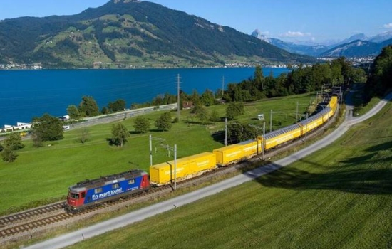 Pociąg Poczty Szwajcarskiej jedzie wzdłuż jeziora