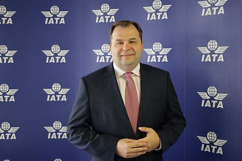 Sebastian Mikosz na tle ścianki z logotypem IATA.