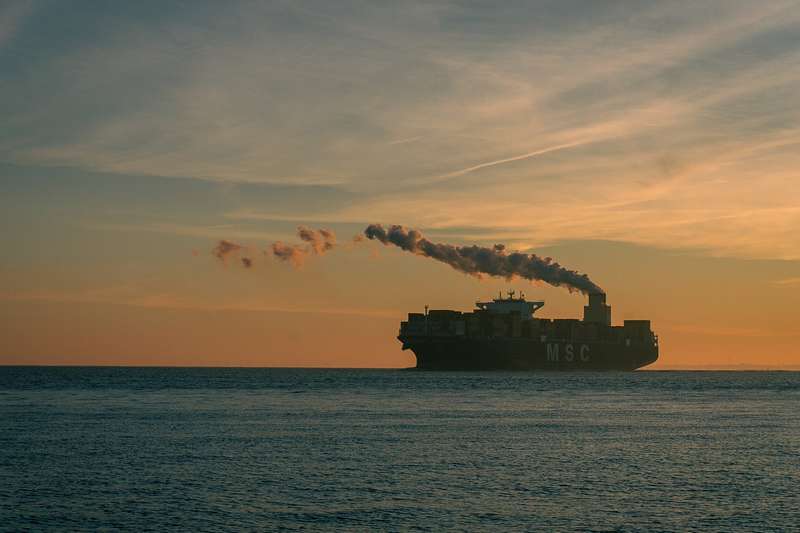Statek kontenerowy na morzu w zachodzącym słońcu